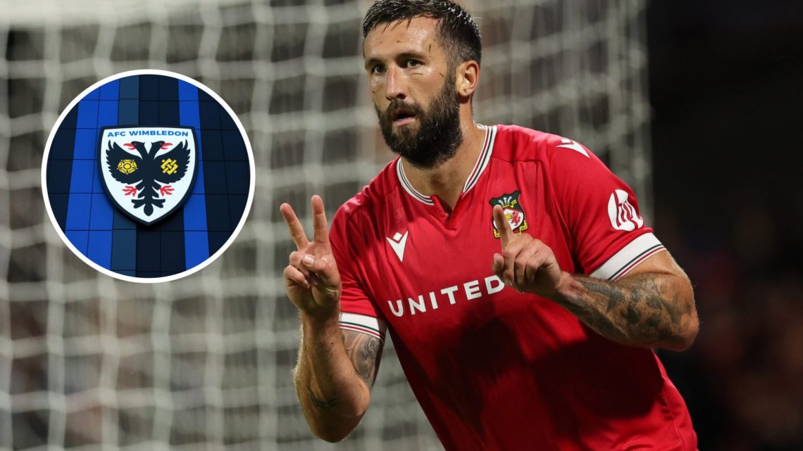Ollie Palmer of Wrexham signals the 2-1 score at the time to the Walsall fans. A detailed view of the AFC Wimbledon badge is seen outside the stadium.